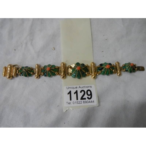 1129 - A yellow metal bracelet with flower shapes in green stone with red centre's (one red stone missing a... 