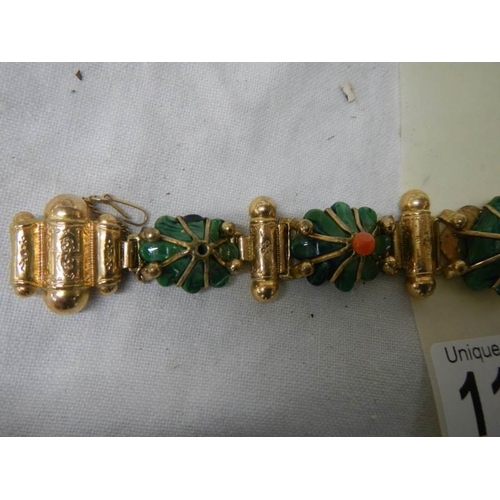 1129 - A yellow metal bracelet with flower shapes in green stone with red centre's (one red stone missing a... 