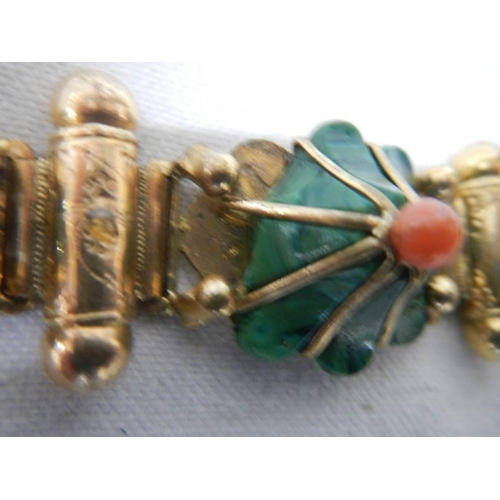 1129 - A yellow metal bracelet with flower shapes in green stone with red centre's (one red stone missing a... 