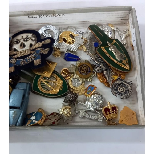 787 - A quantity of military cap badges etc. Including some die cast Dinky