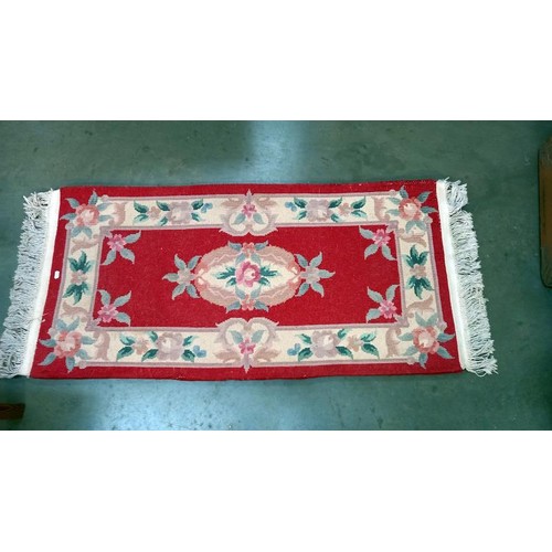 739 - A red coloured rug - 143cm x 63cm (including tassels) COLLECT ONLY