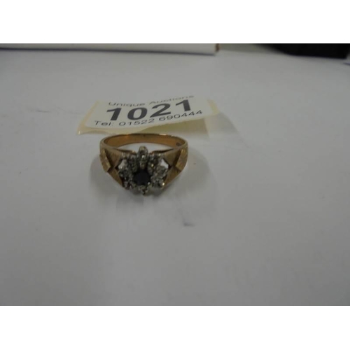 1021 - A 9ct gold cluster ring with central sapphire and diamond chips, size R half, 4.1 grams.