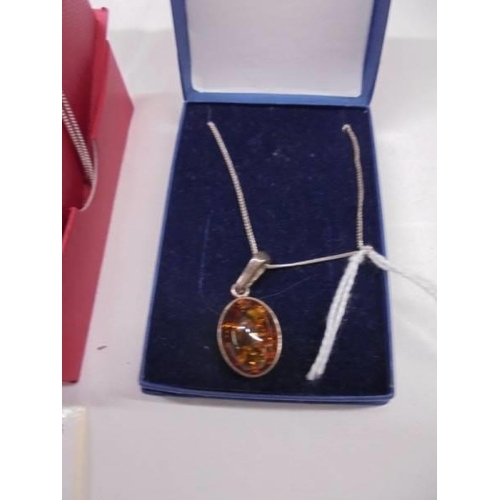 2001 - A silver and mother of pearl heart locket and an unmarked amber pendant.