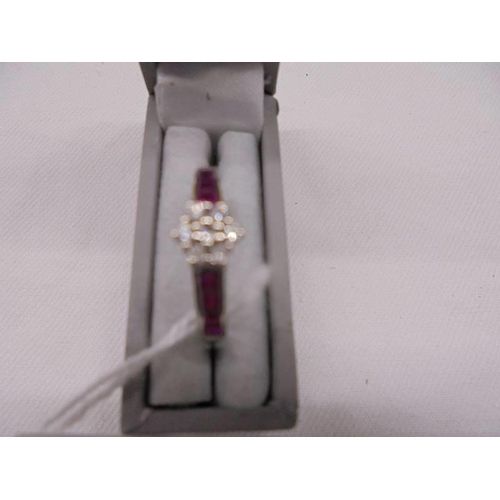 2022 - A floral diamond ring in white gold with ruby set shank. size N, 2.6 grams.