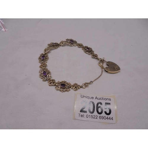 2065 - A 9ct gold bracelet set amethysts with safety chain and padlock, 15.1 grams total.