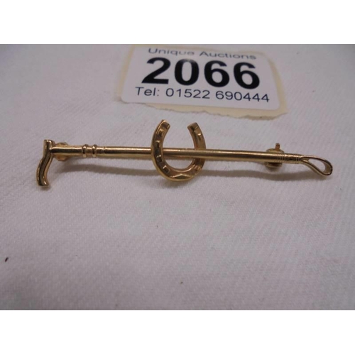 2066 - A 9ct gold brooch in the form of a riding crop and horse shoe, 3.3 grams.