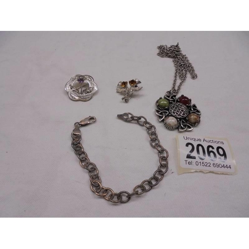 2069 - A silver bracelet, two silver thistle brooches and a white metal Celtic pendant.