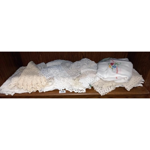 334 - A shelf of linen doilies etc