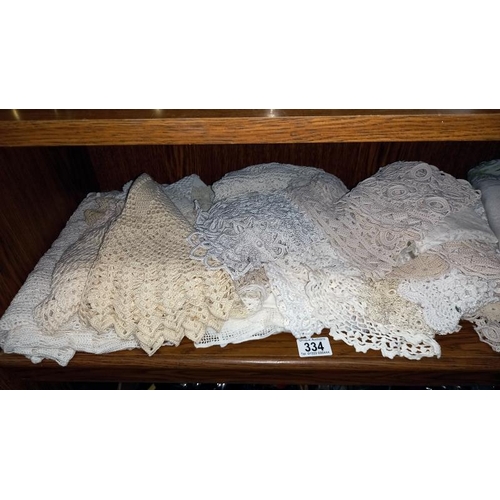 334 - A shelf of linen doilies etc