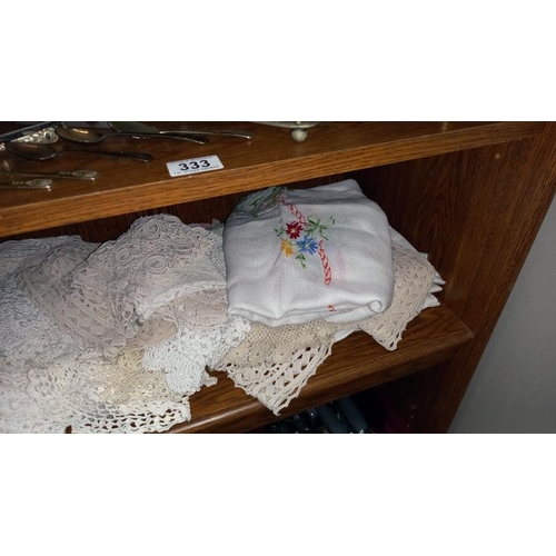 334 - A shelf of linen doilies etc