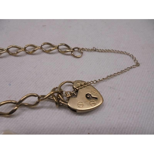 1049 - A 9ct gold wrist chain with padlock and safety chain. 7.6 grams.