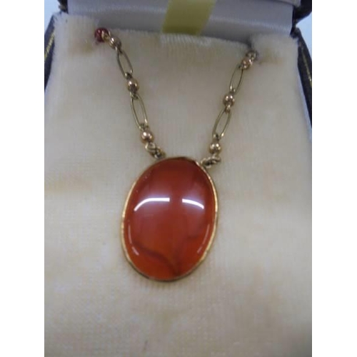 1051 - A 9ct gold pendant set orange stone featuring a Roman head, 5 grams.