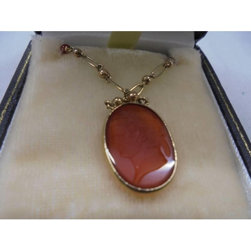 1051 - A 9ct gold pendant set orange stone featuring a Roman head, 5 grams.