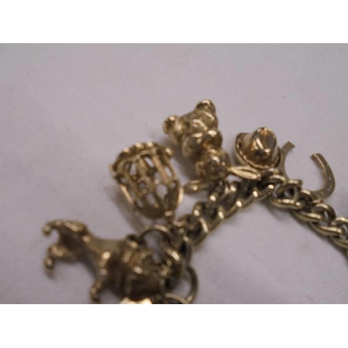 1121 - A gold charm bracelet with forteen charms, 77.7 grams.