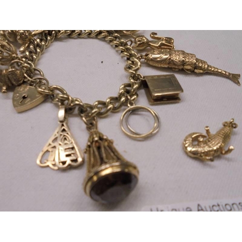 1121 - A gold charm bracelet with forteen charms, 77.7 grams.