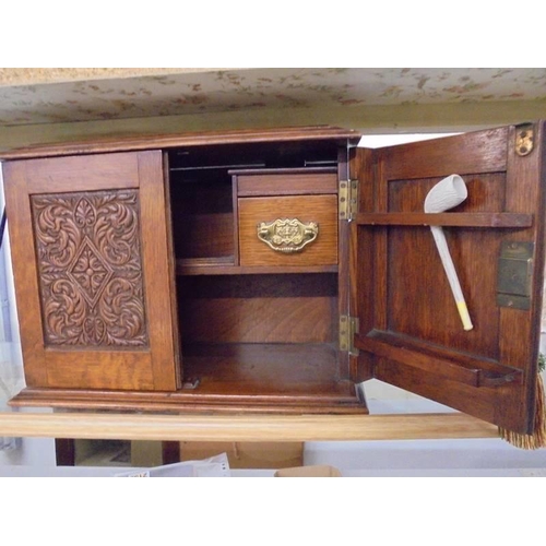 1196 - An oak smokers cabinet with carved doors.