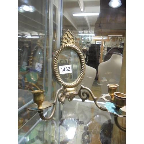 1452 - A pair of small brass wall mirrors with attached candle holders.