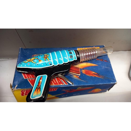 53 - A boxed tinplate The Milky Way boat MF215, made in China and a vintage space gun