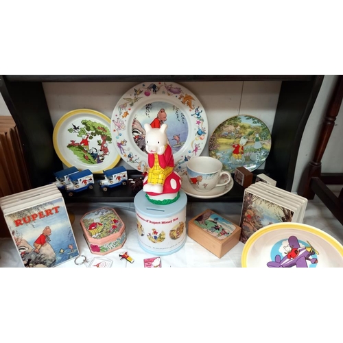 252 - A good selection of Rupert The Bear collectables including pin badges, tins, mugs & money boxes etc.... 