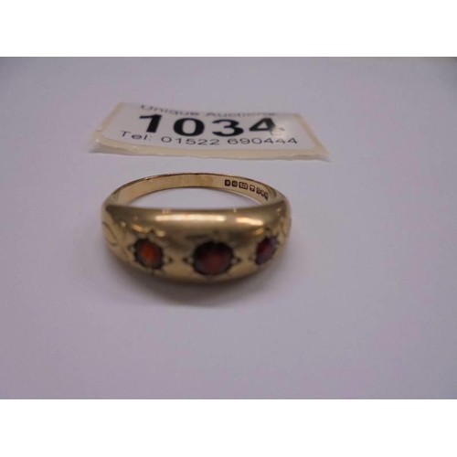 1034 - A 9ct gold three stone garnet ring, size P, 3.15 grams.