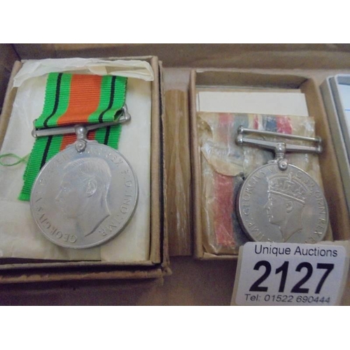 2127 - Two WW2 medals for Kenneth Foster and R J Mawer together with an RAF cap badge belonging to 1135011 ... 