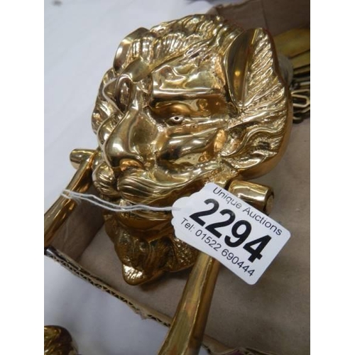 2294 - A brass lion head door knocker and other brassware.