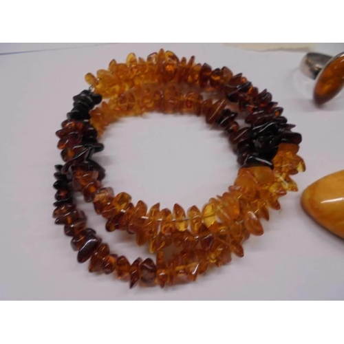 1123 - An amber necklace, amber bracelet, amber set ring, amber fish on rock and two amber stones.