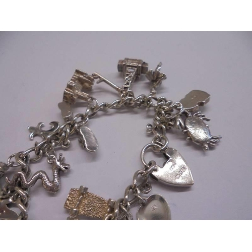 1041 - A silver charm bracelet with padlock and 22 charms (2 marked 925, others not marked) and 4 charms.