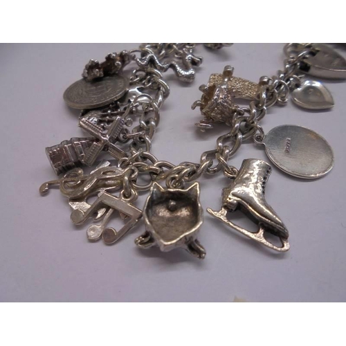 1041 - A silver charm bracelet with padlock and 22 charms (2 marked 925, others not marked) and 4 charms.