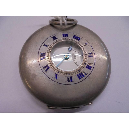 1057 - A silver half hunter pocket watch in working order but missing glass on a carved wooden stand.