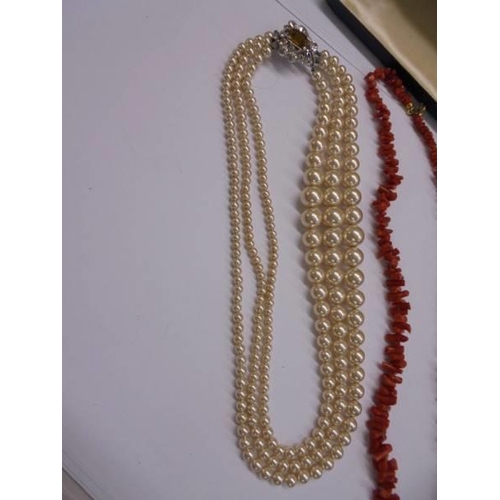 1094 - A three strand pearl necklace and a coral necklace.