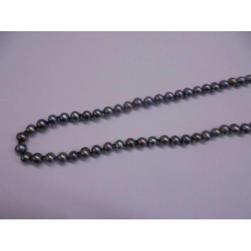 1100T - A necklace of grey pearls.