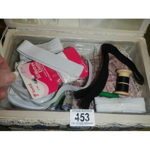 453 - A needlework box with contents including threads.