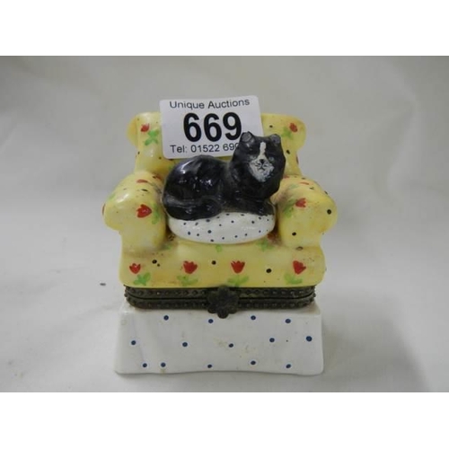 669 - A pill box featuring a cat sat in an armchair.