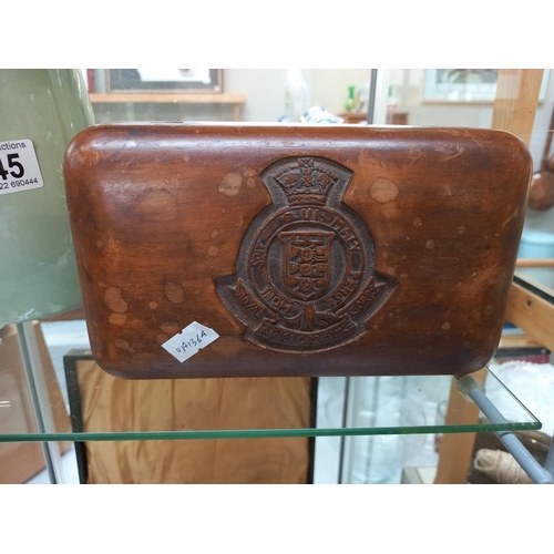 246 - A carved teak box with Royal Army Ordnance Corps emblem and contents of military buttons and badges