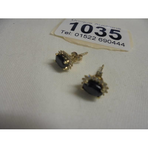 1035 - A pair of oval sapphire and diamond yellow earrings. 1.2 grams