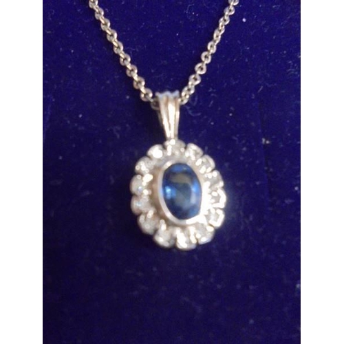 1040 - A white gold sapphire and diamond pendant on a yellow metal chain.