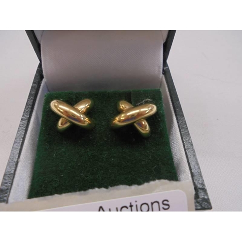 1054 - A pair of 9ct gold earrings in a ribbon designm