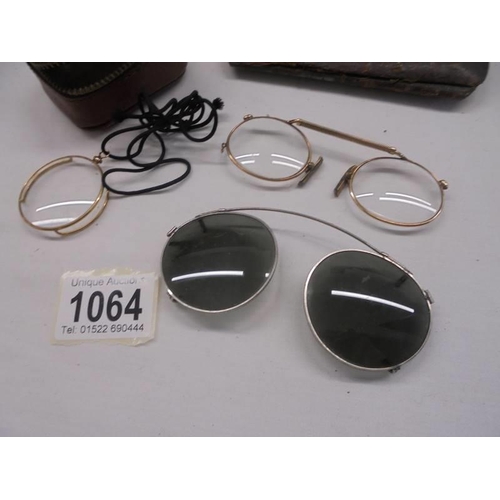 1064 - A vintage gilded monacle eye piece, clip on sunglasses and one other.