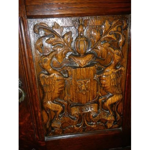 622 - A two door cupboard with carved doors depicting coats of arms, COLLECT ONLY.