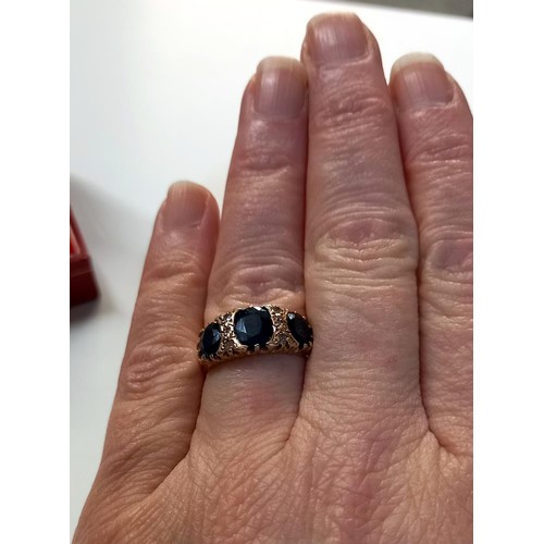 1060B - A 9ct gold ring wit dark blue stones, Size O (3.6g)