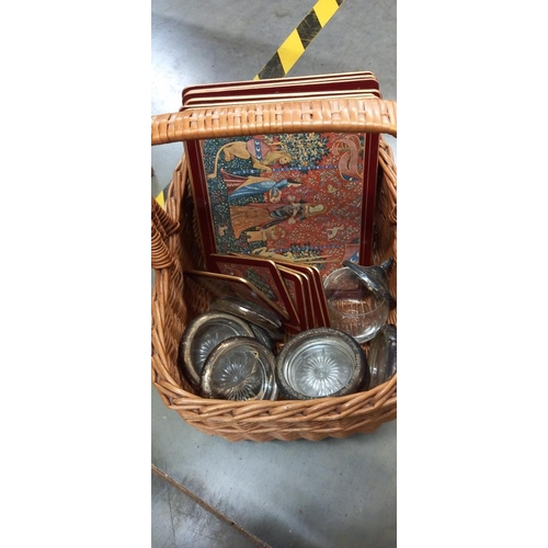 142 - A wicker basket with glass and silver plate coasters plus placemats and Royal Worcester Evesham ware... 