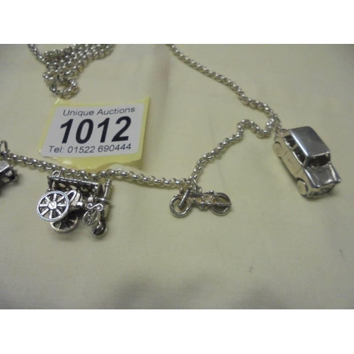 1012 - A long silver chain with six transport related charms,