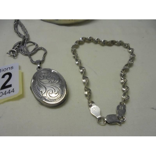 1022 - A silver locket, a silver bracelet and a silver bangle (bangle has dint). 36 grams (1.3 ozs).