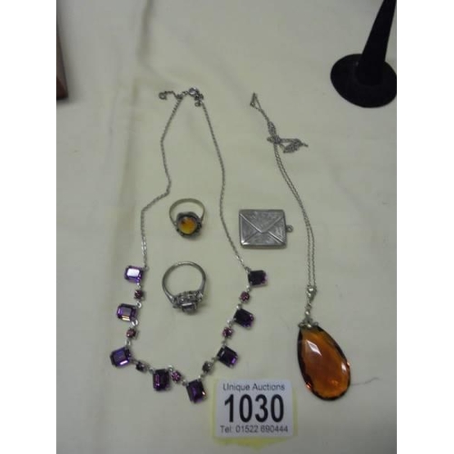 1030 - A small silver stamp locket, two silver rings and a pendant.