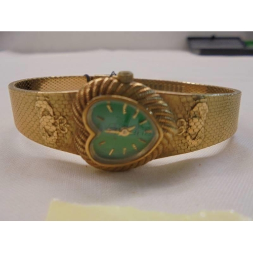 1063 - A heart shaped Irish watch with green dial and Claddagh designs to both shoulders in yellow metal.