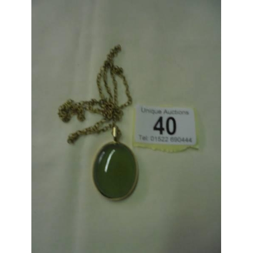40 - A green stone pendant in a 9ct gold mount with a yellow metal chain.