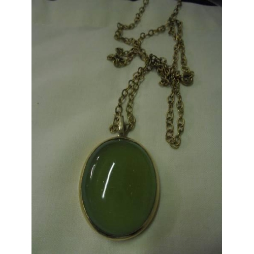 40 - A green stone pendant in a 9ct gold mount with a yellow metal chain.