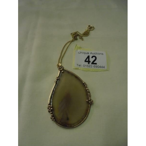 42 - A large stone set pendant in 9ct gold mount with a yellow metal chain.