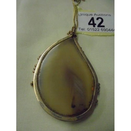 42 - A large stone set pendant in 9ct gold mount with a yellow metal chain.